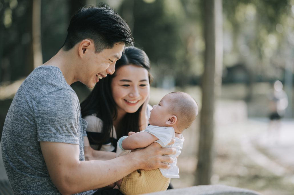 Asian Chinese Parents bonding with their baby boy in public park during weekend morning